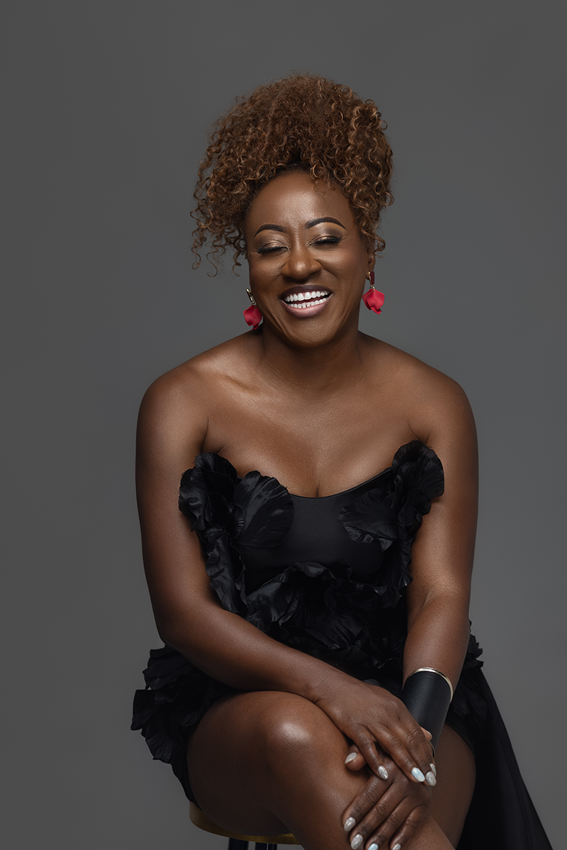 Diva Doc host seated and smiling in a black dress