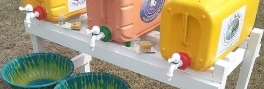 Water containers with taps above basins at a handwashing station